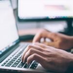 A professional working on their laptop to access information using a self-service knowledge base of their organization.